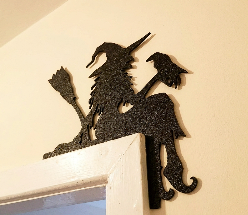 Decorative black witch wall art on a white surface with a neutral background