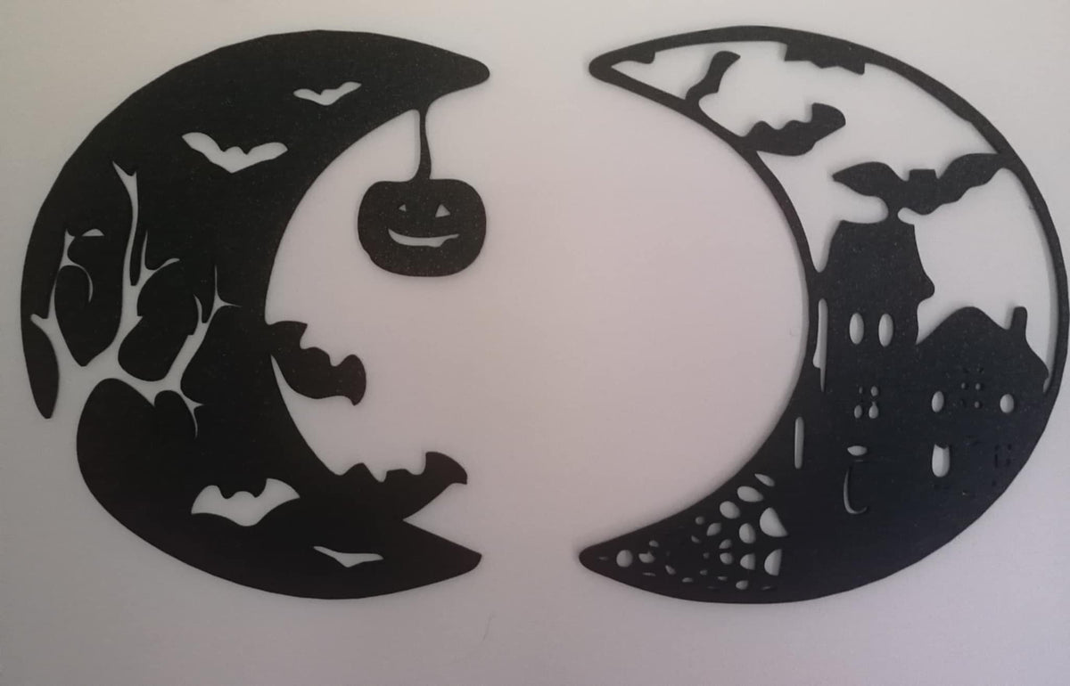Two black crescent‑moon silhouettes featuring Halloween cut‑outs, including bats, branches, a haunted house, and a hanging jack‑o’-lantern, displayed on a white background.