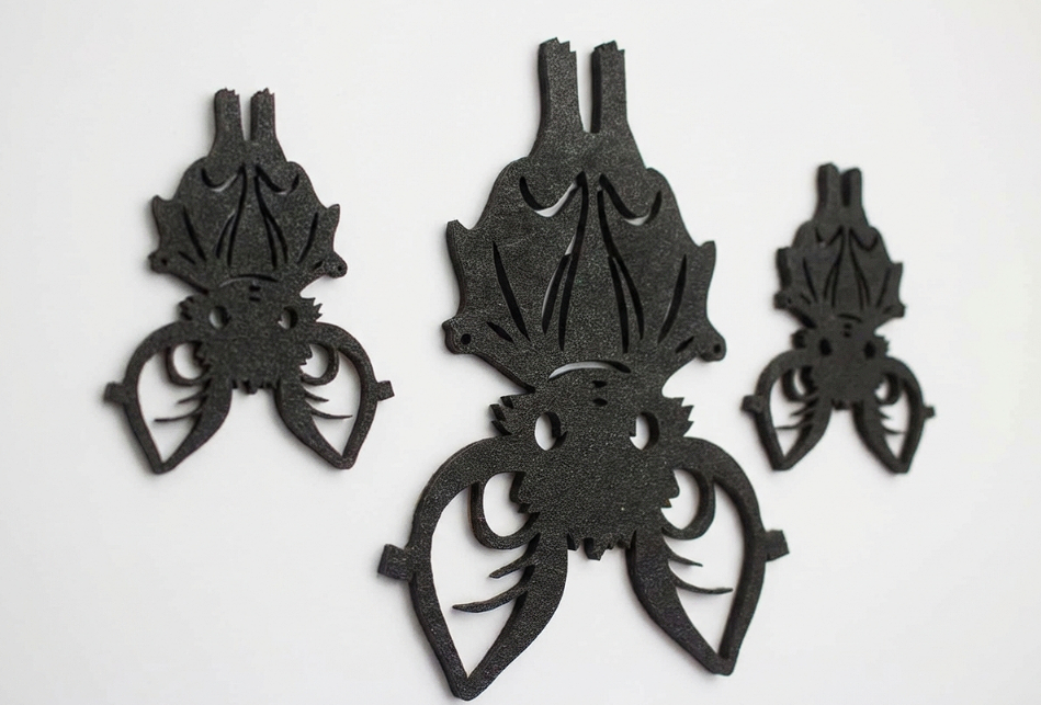 Three black bat-shaped decorative cutouts or wall decals arranged on a plain white background.