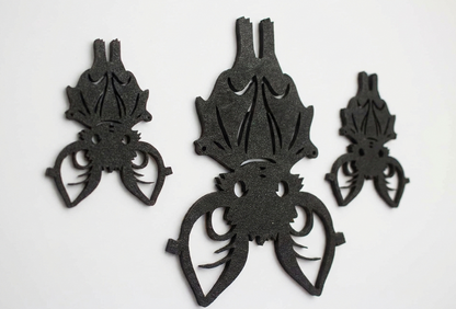 Three black bat-shaped decorative cutouts or wall decals arranged on a plain white background.